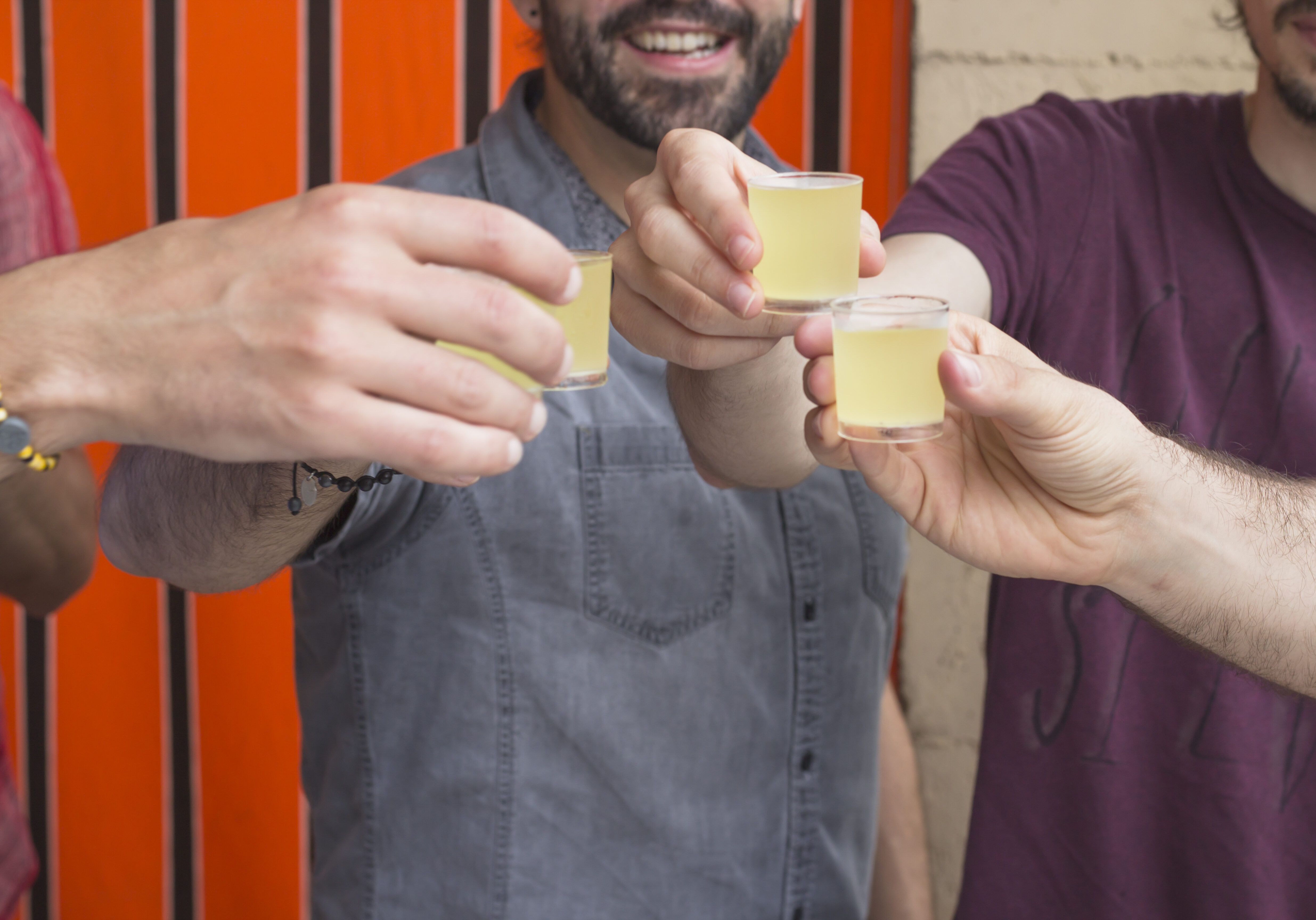 Young men toasting with shots during a celebration in a country house.